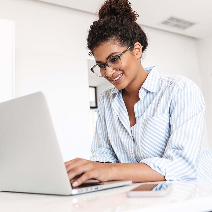 smiling entrepreneur with glasses browsing the web on a laptop
